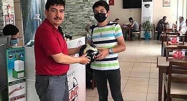  Muhtar Suat Gölcük mahallesindeki çalışkan öğrencilerin karnesini getirmesi sonucu futbol topu hediye etti